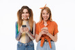 © Drobot Dean - Full length portrait of two gorgeous girls wearing casual clothes smiling and holding smartphones