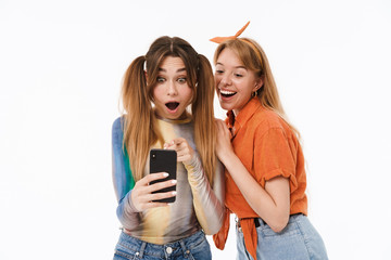 Poster - Full length portrait of two teenage girls wearing casual clothes having fun and using smartphone together