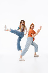 Wall Mural - Portrait of two caucasian girls wearing casual clothes screaming and doing karate gestures