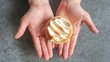 Woman hand holding lemon tart or pie topped by meringue against grey background