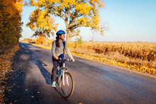 Young Bicyclist Riding On Autumn Field Road At Sunset. Happy Woman Traveler Smiling