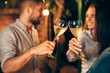 closeup of young couple making a toast with white wine. outdoor at the evening