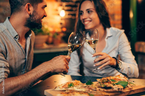 Fotografía young couple making toast with wine, at home in garden, evening scene