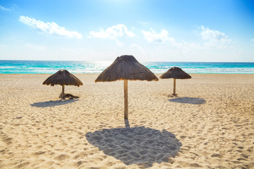 Wall Mural - Empty beach with three thatched sun umbrellas