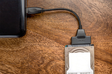 hdd 2.5 internal hard drive disk connected to laptop via sata usb cable on wooden table closeup view