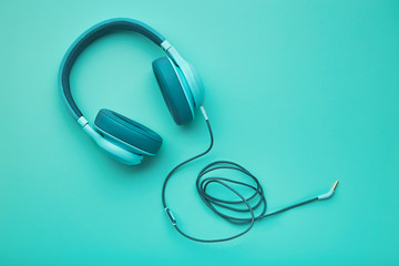 Turquoise headphones on a colored background. Music concept with copyspace. Colored headphones isolated