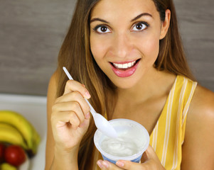 Wall Mural - Brazilian woman eating light yogurt at home. Close up from above. Healthy concept.