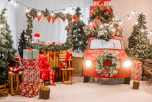 Magic Card In Red Color. Decorated Retro Car With Festive New Year Lights, Garlands, Branches Of Christmas Trees, Gift Boxes In White-green Wrapping Paper, A Wreath Of Pine Needles. Copy Space Texture