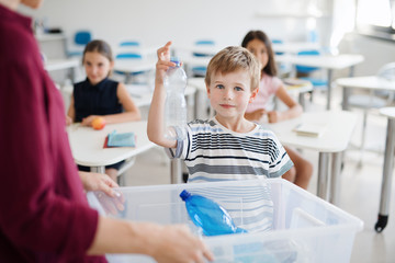 A teacher with small school kids in classroom learning about waste separation.