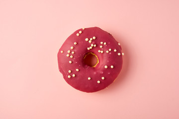 Wall Mural - red round donut with white sprinkles on a pink background