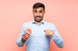 © luismolinero - Young man holding a donut over isolated pink background with surprise facial expression