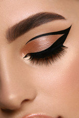 luxury female make-up close-up with eyeliner and golden eye shadow