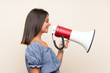 © luismolinero - Young girl over isolated background shouting through a megaphone
