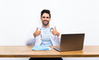 © luismolinero - Young doctor man with his laptop over isolated wall giving a thumbs up gesture