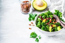 Green Kale Salad With Cranberries And Avocado In White Bowl. Healthy Vegan Food Concept.