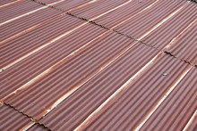 A Red Corrugated Roof At Diagonal View. Tin Plates On The Roof Of Building.