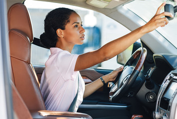 Side view of woman adjusting rear view mirror while driving a car