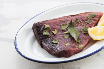 Wall Mural - raw tuna with lemon and bay leaf on ceramic background