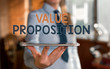 © Artur - Writing note showing Value Proposition. Business concept for feature intended to make a company or product attractive Blurred woman in the background pointing with finger in empty space