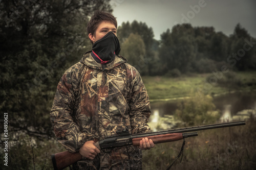 Teenager hunter with face mask and gun during duck hunting season