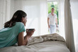 © Westend61 - Germany, Hamburg, Woman lying on bed holding cup of tea, man in background