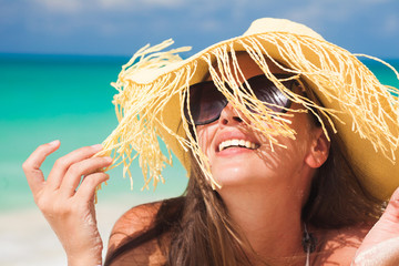 Young woman in bikini and straw hat relaxing at white caribbean beach