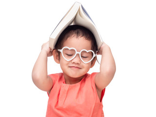 Asian little cute girl wearing glasses and put the book on head. Preschool lovely kid with the book covering on her head smile and close one's eyes. Learning and education of kid.