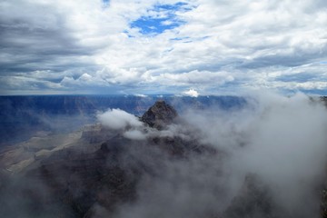 clouds and fog swirl around craggy outcropping at north rim of grand canyon