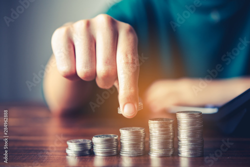 Fotomural Hand putting money coin on each line rising - business saving money concept fo