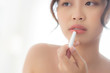 © NT_studio - Beautiful portrait young asian woman looking mirror applying makeup lipstick at room, beauty lips asia girl makeup and cosmetic fashion on mouth at home, lifestyle and health care concept.