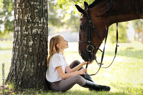 Fotografía Girl teenager jockey sits in a green clearing under a tree
