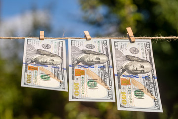 100 dollar banknote on hanging green nature background. Dollar bills hanging on a rope. Close up