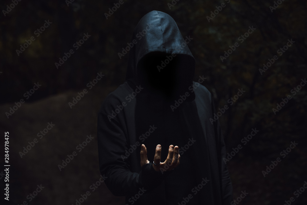 Man in a hood with light on his hand - obrazy, fototapety, plakaty 