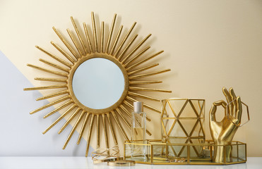 Composition with golden accessories and jewelry on dressing table near color wall