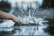 The hand slaps the water surface and creates splashes against a blurred background. Side view. 