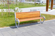 Bench in the summer square, an empty bench for rest. Empty wooden bench in a city park. Wooden bench in the park on a beautiful summer day