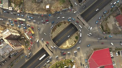 overhead drone shot of traffic driving over roundabout with highway tunnel underneath, infrastructur