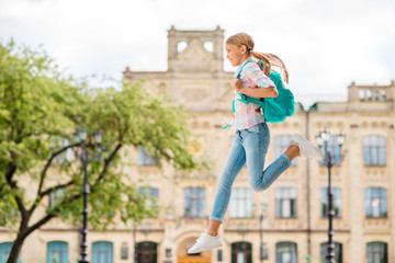 Wall Mural - Full size photo of cheerful girl with rucksack backpack hurrying to academia wearing checkered plaid t-shirt denim jeans outdoors