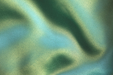 dark green colored background of soft draped fabric. beautiful satin silk textured cloth for making 