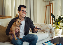Smiling Man Sitting With His Dog Watching The Television At Home