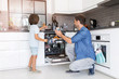 © pikselstock - Father and son loading dishwasher together