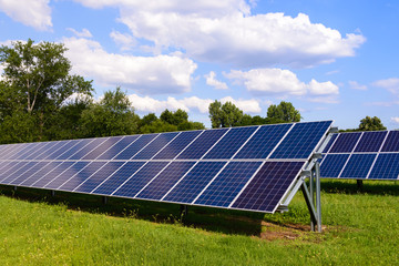 solar panels mounted on the ground. green grass and blue sky background