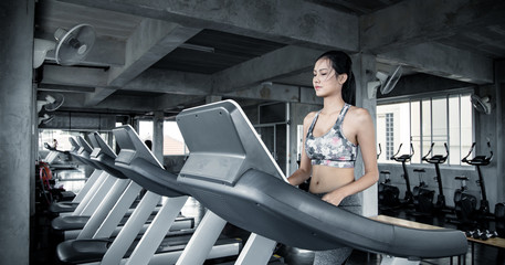 Wall Mural - Asian women exercising on the running machine in the gym.