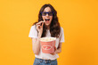 © Drobot Dean - Happy cheerful smiling young woman posing isolated over yellow wall background eat popcorn watch film.