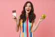 © Drobot Dean - Happy emotional cute woman posing isolated over pink wall background holding apple and chocolate.