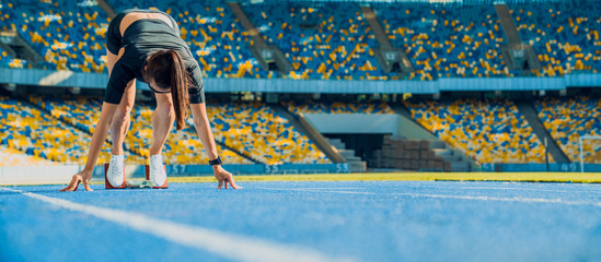 Wall Mural - Female athlete taking position on her marks to start off the run