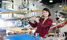 Smiling Woman Showing Sports Biplane Model She Created In Aircraft Workshop