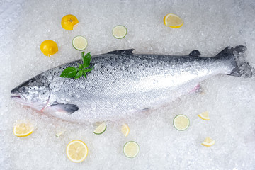 fresh red whole fish, lies on ice, headless, with green basil, light