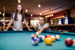 © RomanR - Beautiful woman with her friend playing billiard in pub