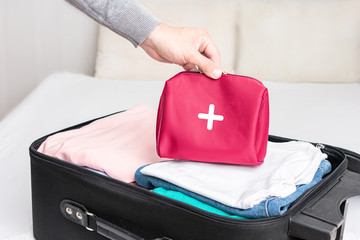 A man collect the suitcase on the trip, clothes for the road and first aid kit for extraordinary event, men's hand, top view, cropped image, toned